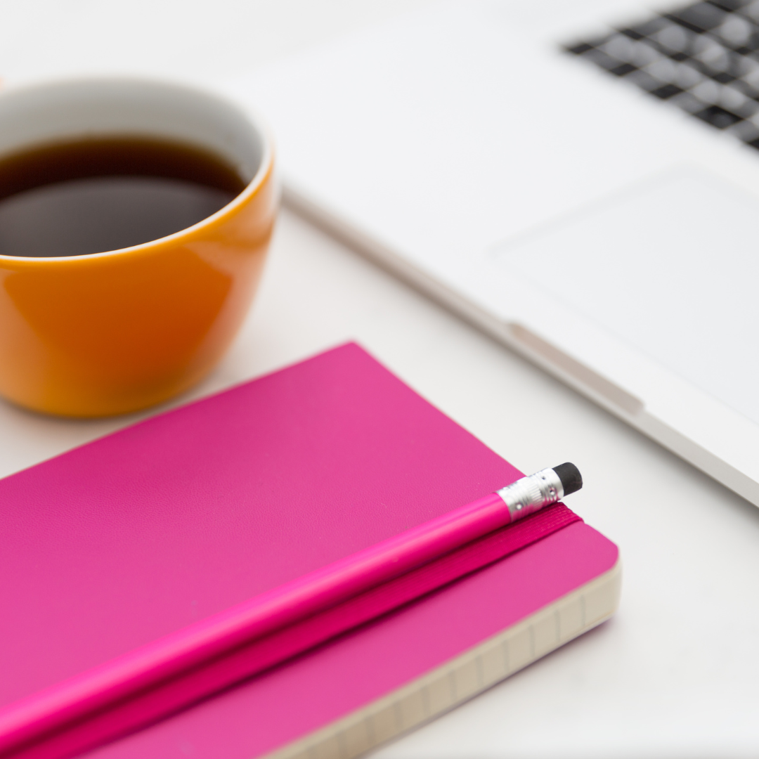 Victoria Brown discusses how to make your business plans work in her Creative Slurp podcast, with an image of a bright pink notebook and pencil, an orange cup filled with black coffee next to a laptop.